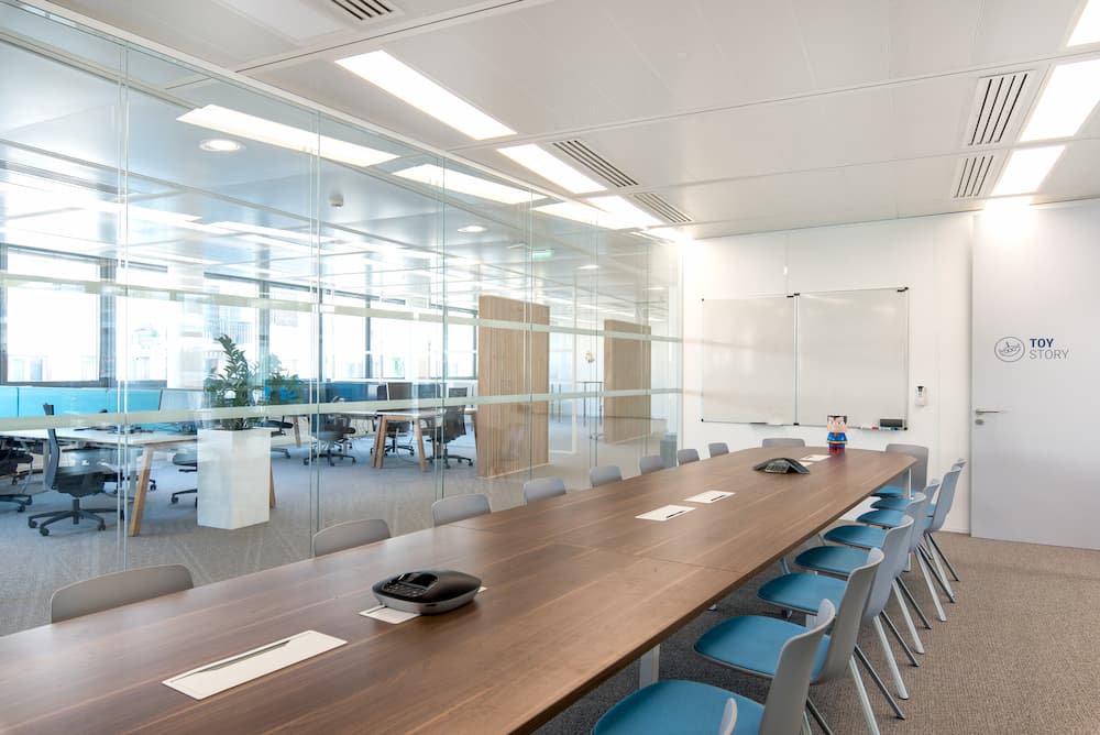Aménagement d'une grande salle de réunion connectée avec des vitres transparentes pour avoir une vue sur les espaces de travail
