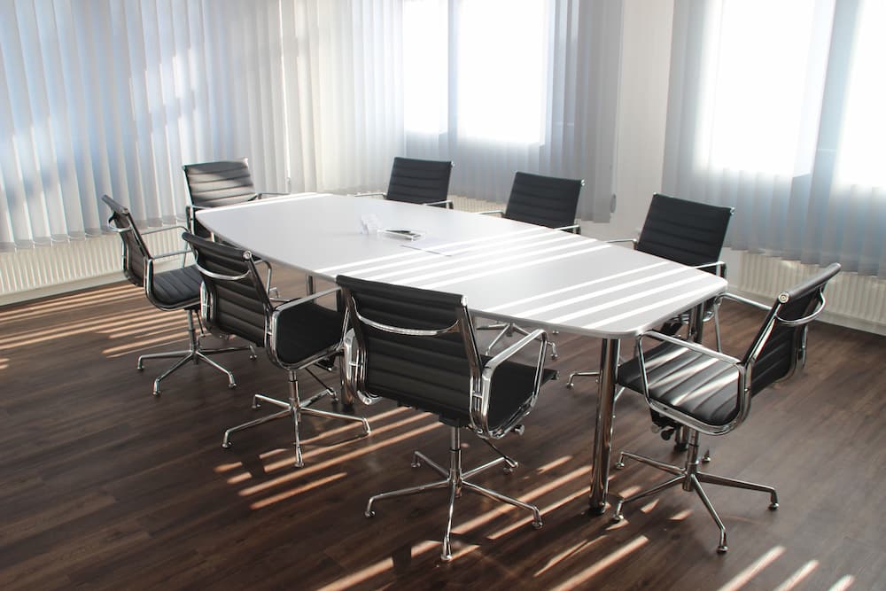 Salle de réunion avec 8 chaises noires ergonomiques et une table blanche design
