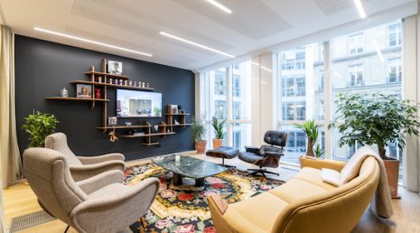 Aménagement d'un espace de convivialité dans un bureau professionnel pour se sentir comme à la maison. L'espace est composé de fauteuils, canapés et plantes pour offrir un côté chaleureux.