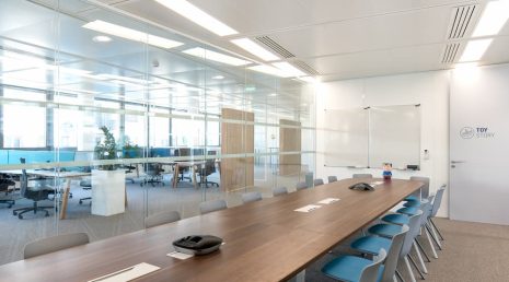 Aménagement d'une grande salle de réunion connectée avec des vitres transparentes pour avoir une vue sur les espaces de travail